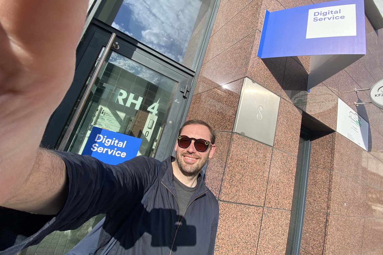Selfie of Martin Jordan, new Head of Design at the German government’s Digital Service in front of the outside door – with 2 signs saying Digital Service in the background