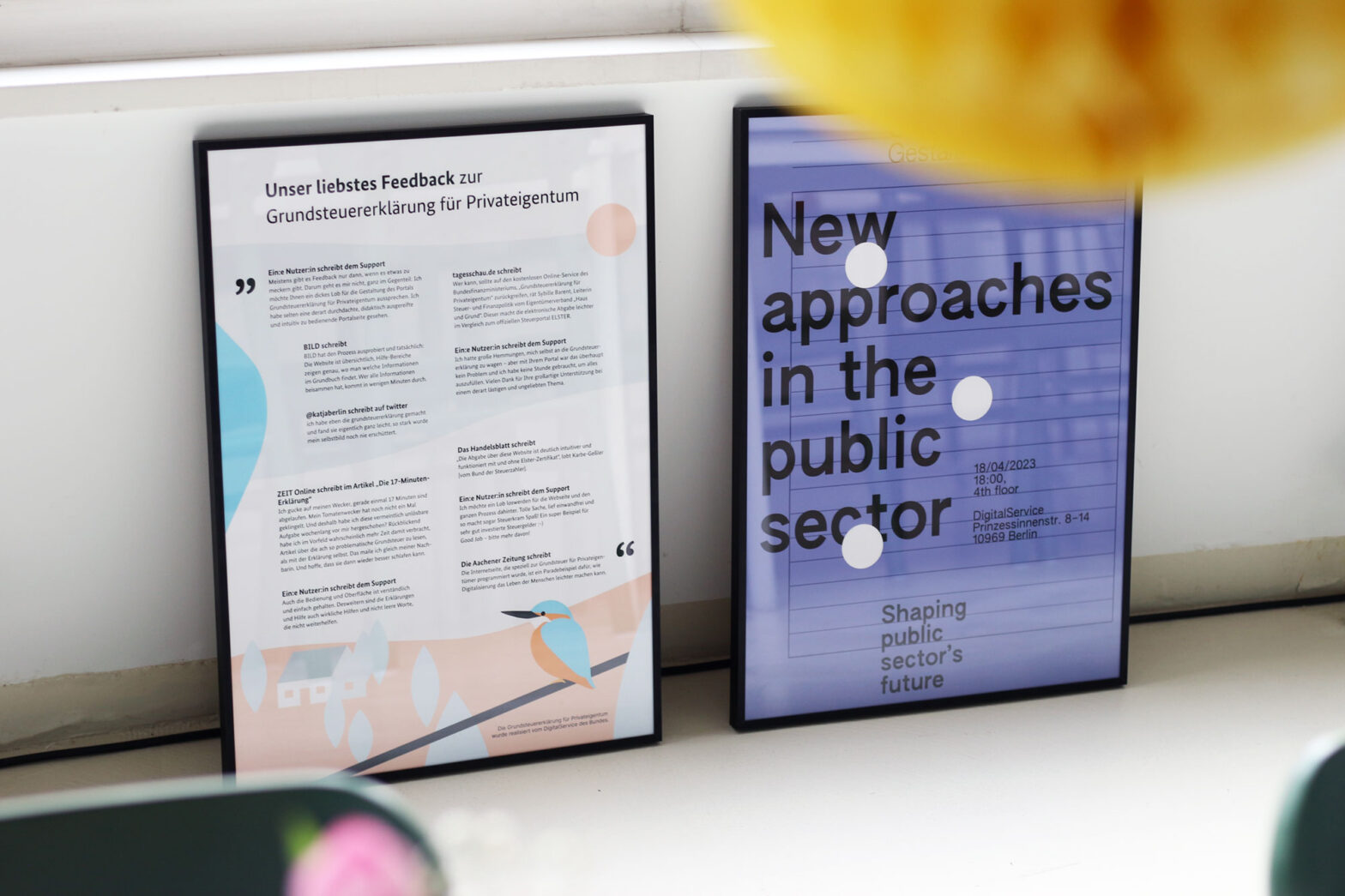 Two posters framed in metal frames standing on the floor leaned against a wall – one is detailled with various small quotes, the other has a big phrase: ‘New approaches in the public sector’