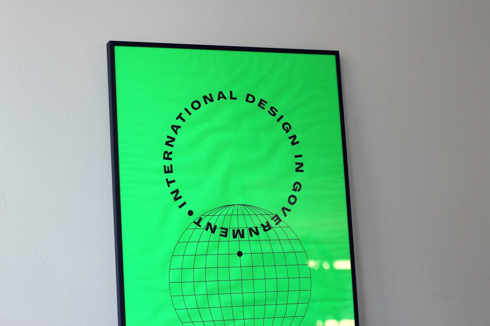 A neon bright green poster with a simplified depiction of a globe and the words ‘International Design in Government’