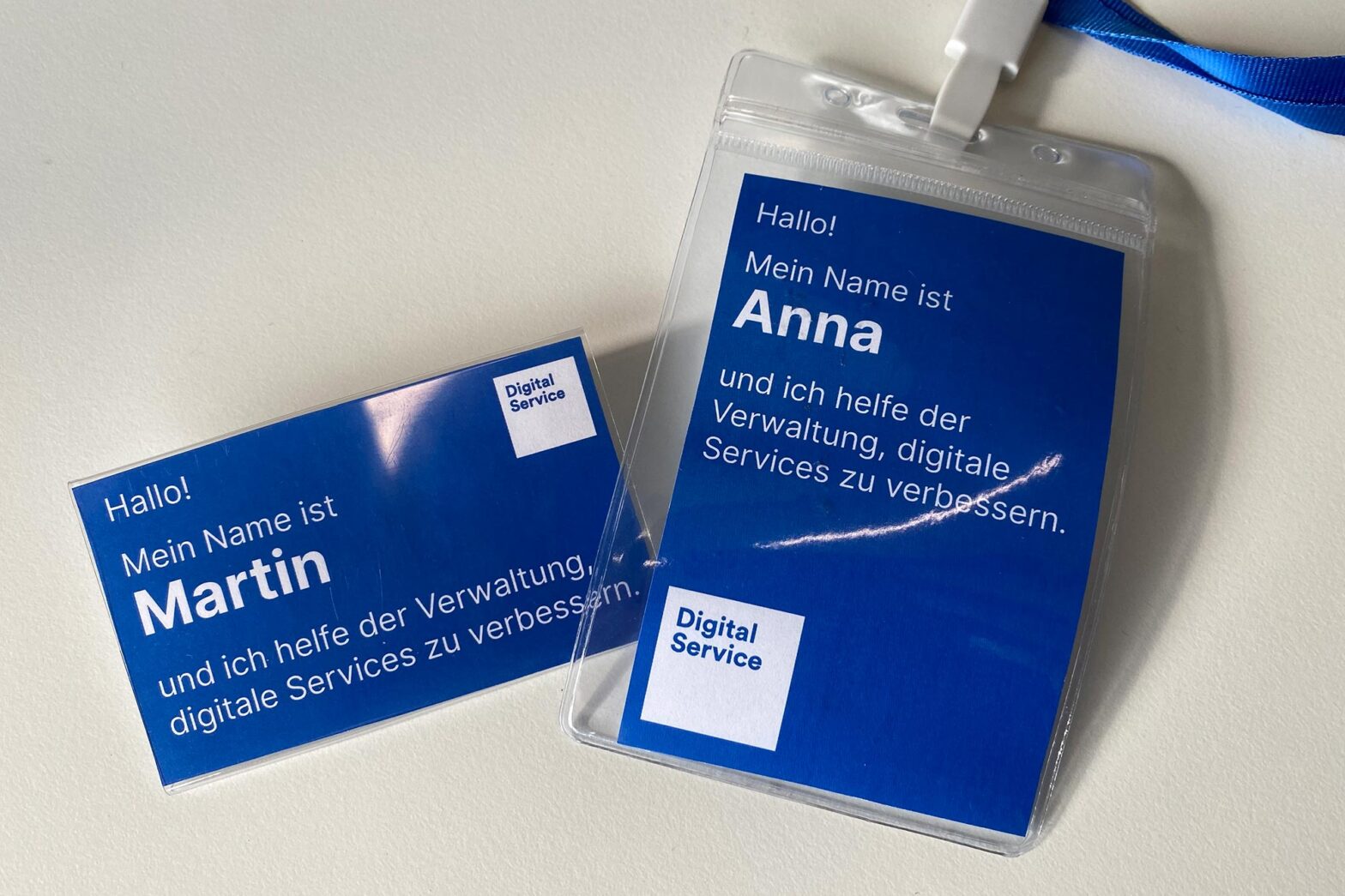 Two name badges for Martin and Anna next to each other saying in German: ‘Hello! My name is … I help government improve public services’ with the logo of the Digital Service.