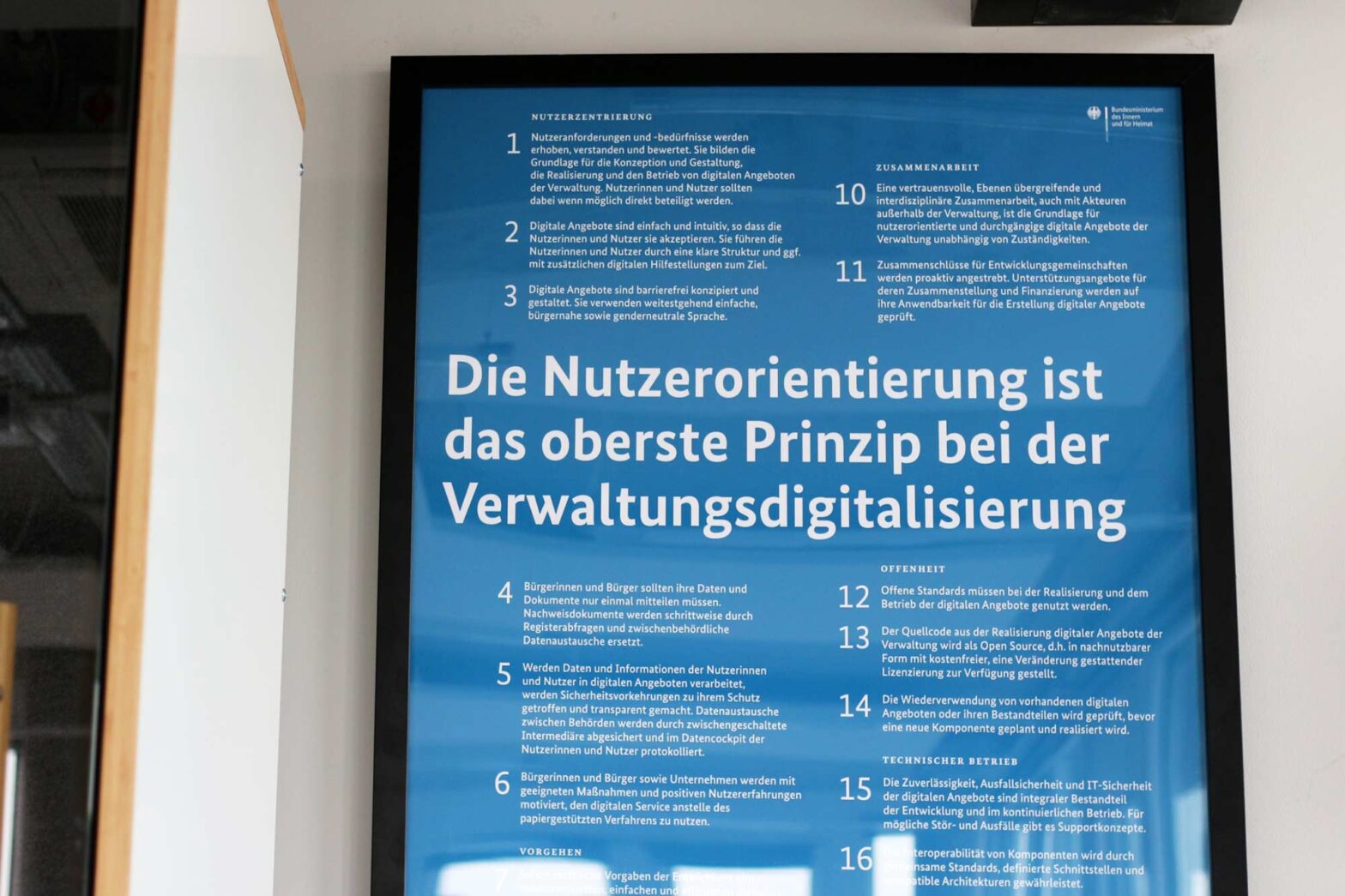 A framed poster of the German government’s Service Standard on a wall, listing at least 16 points; a big caption on top says in German: “User-centricity is the key principle when digitalising administration”