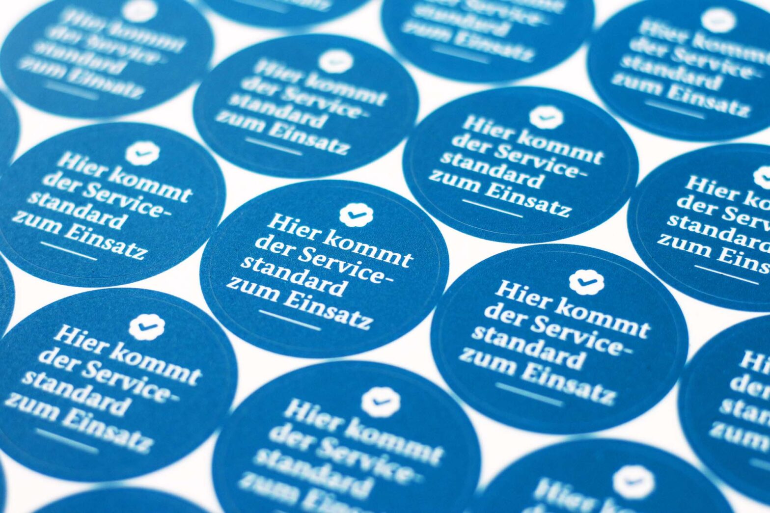 A sheet with dozen of circular stickers saying in German: The Service Standard is used here
