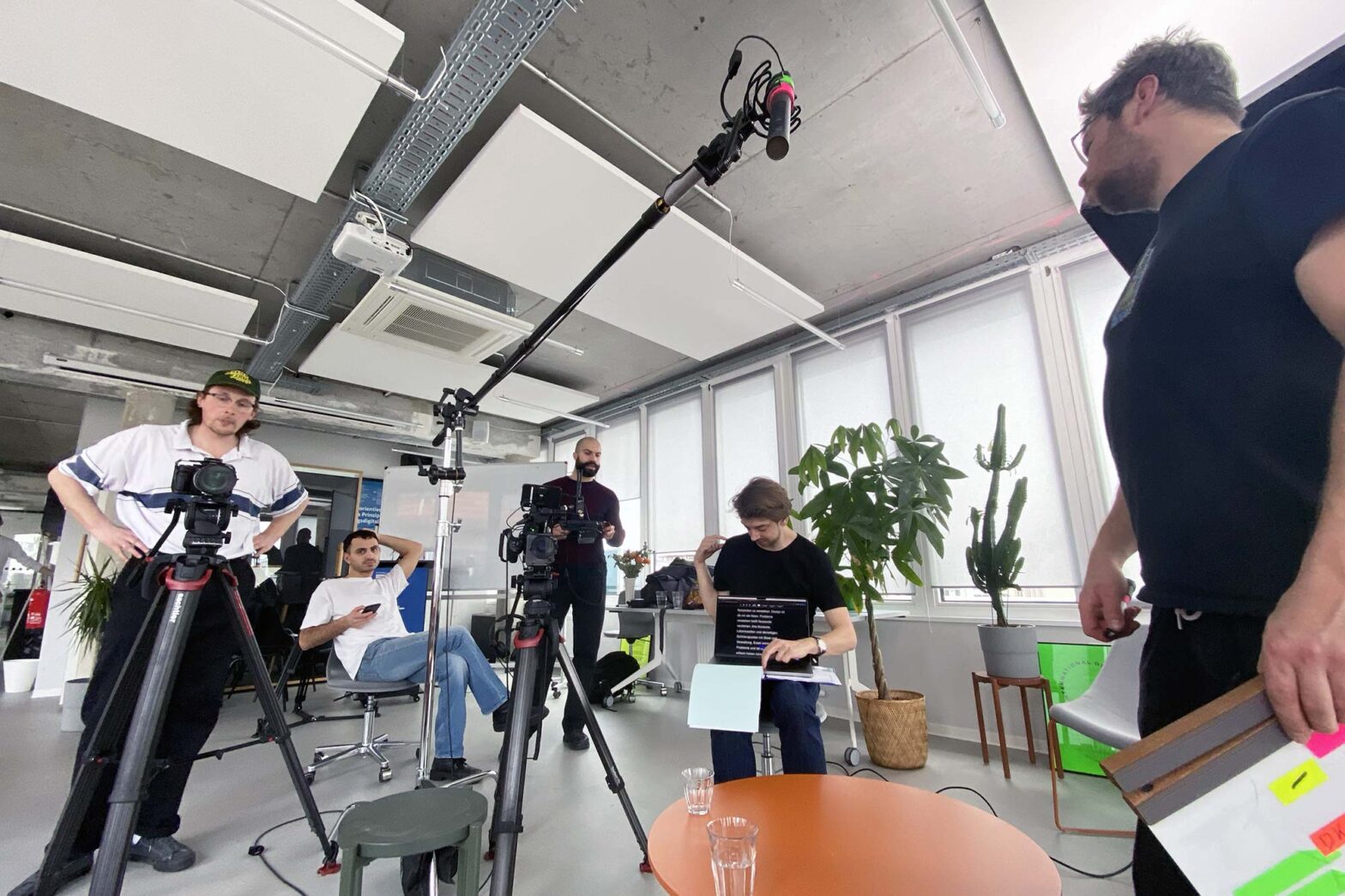 A group of 5 men with professional camera equipment in a modern office space with bare concrete walls