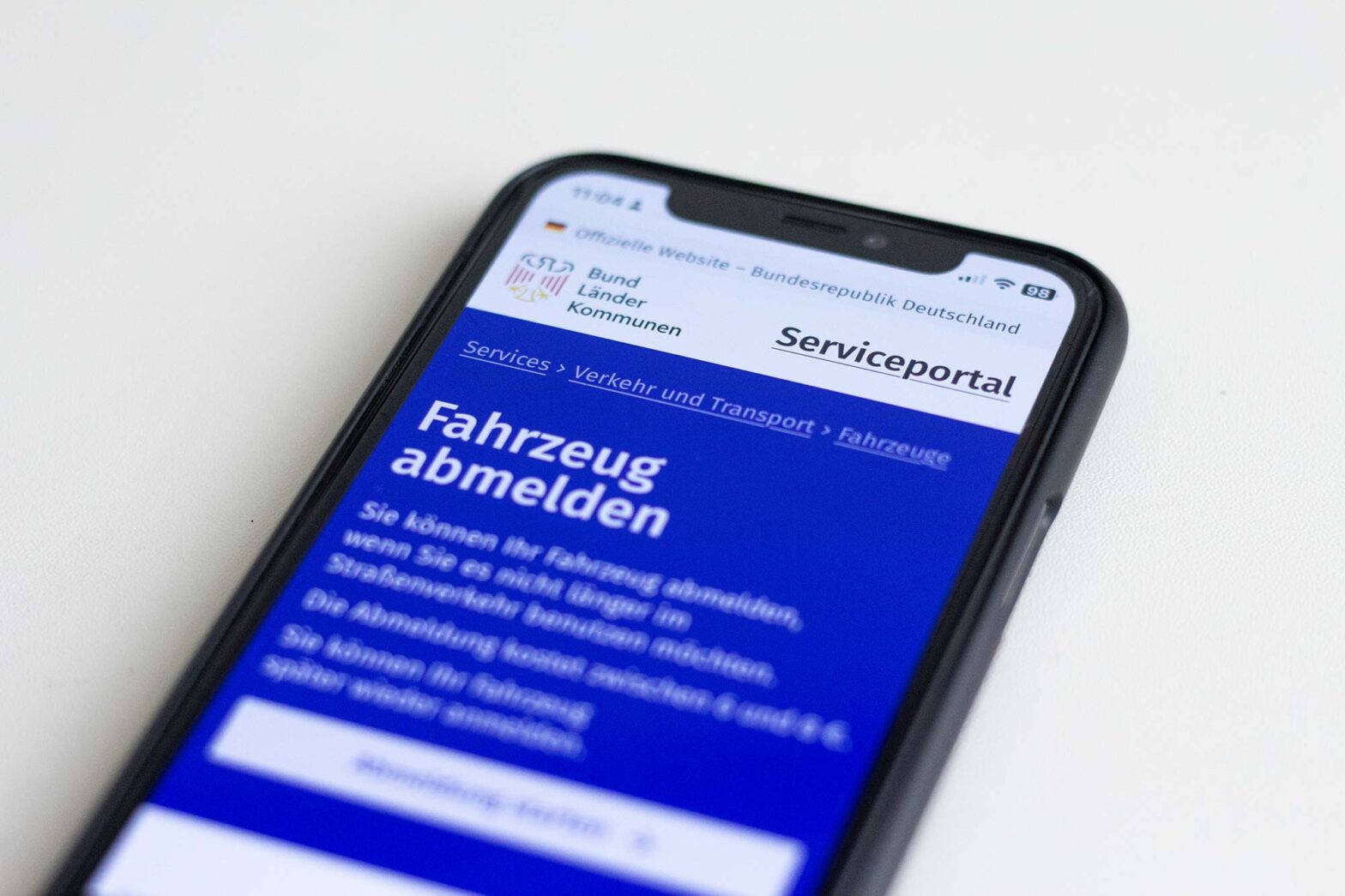Phone on bright surface displaying a German government service on a Federal service portal to take a car off the road
