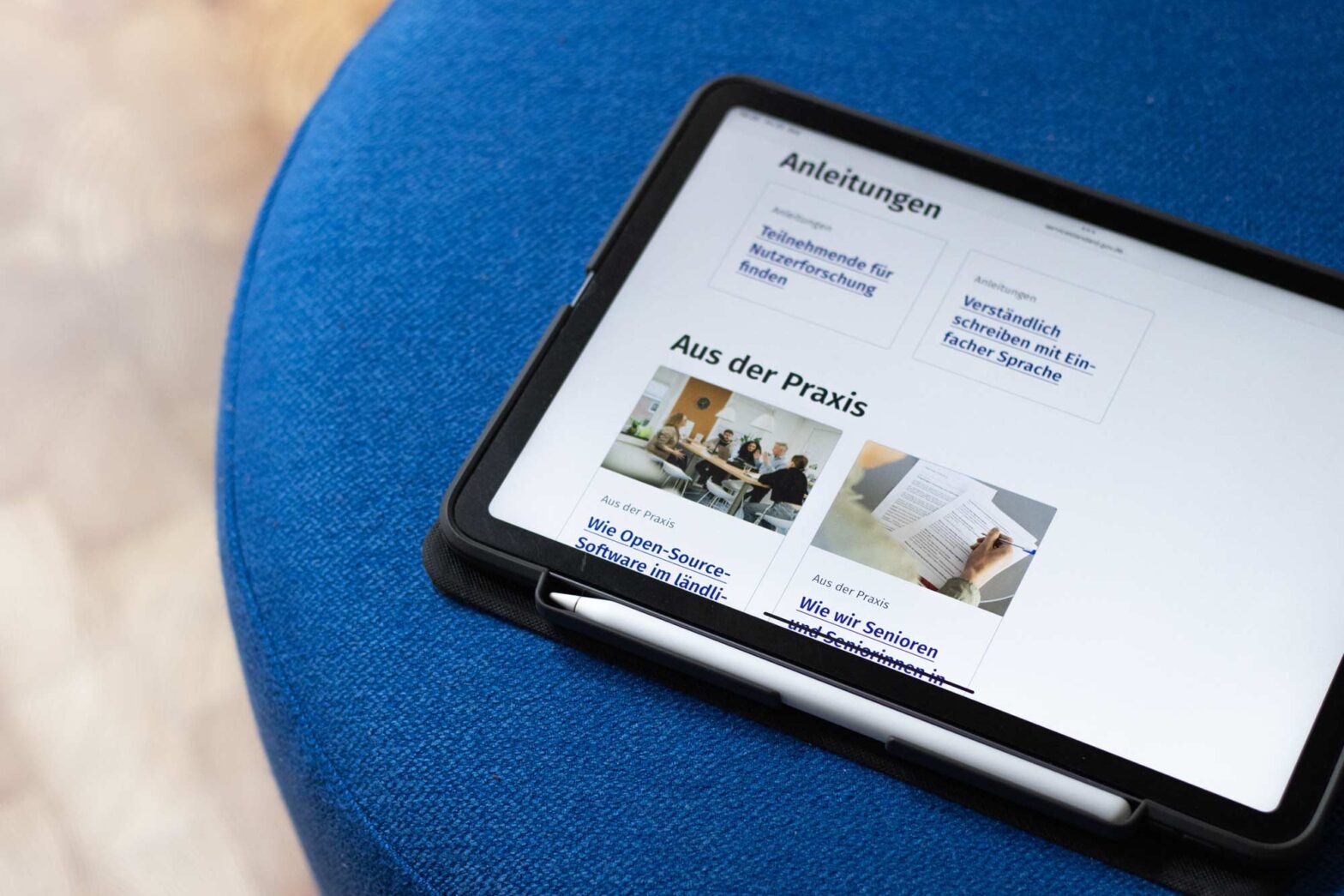 A tablet computer on a blue pouff displaying a website listing 2 pieces of government guidance and 2 practice reports from service teams