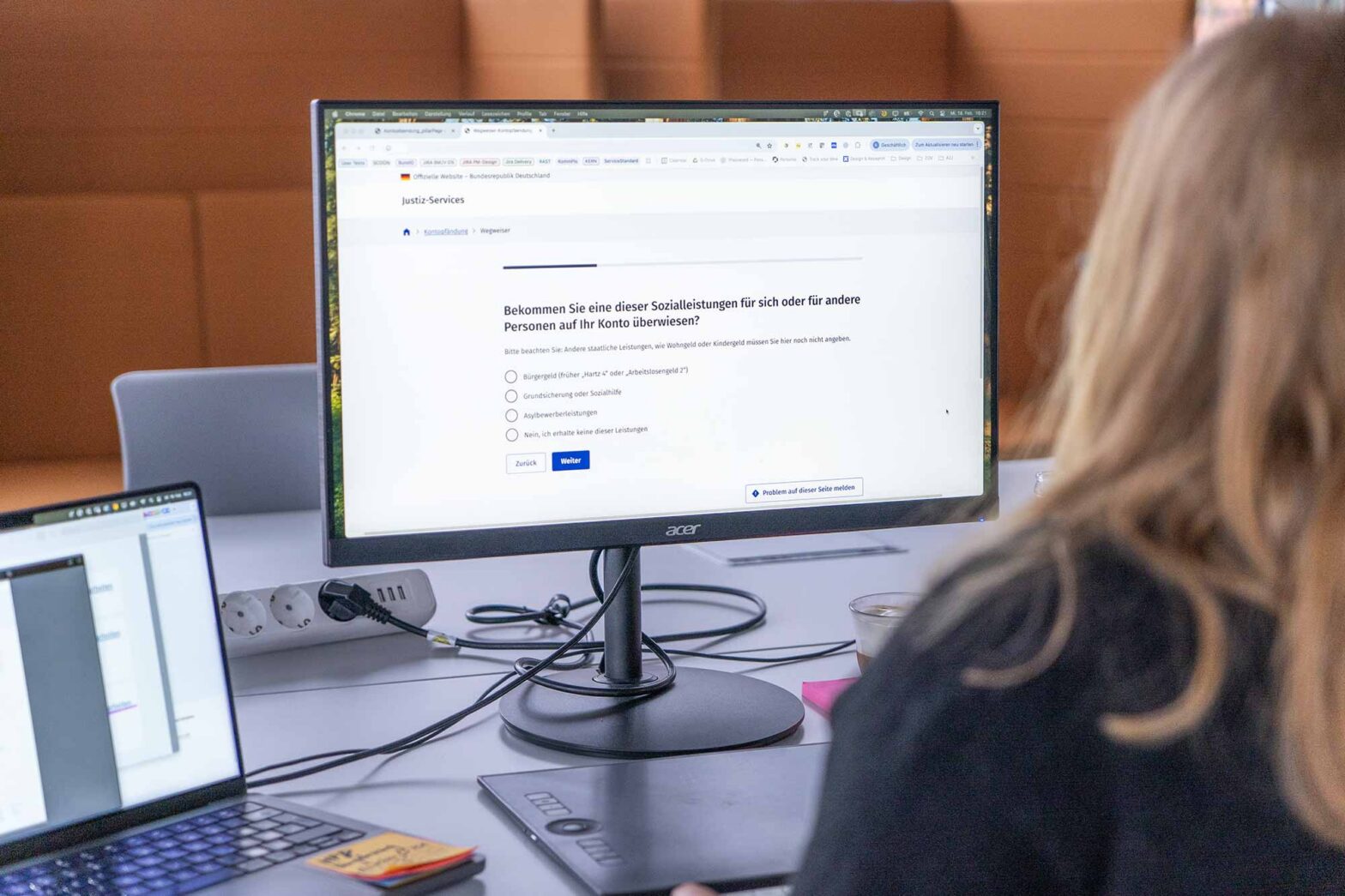 Person sitting in front of a computer monitor displaying a digital legal form and asking a question about receiving social benefits – with 4 different possible answers