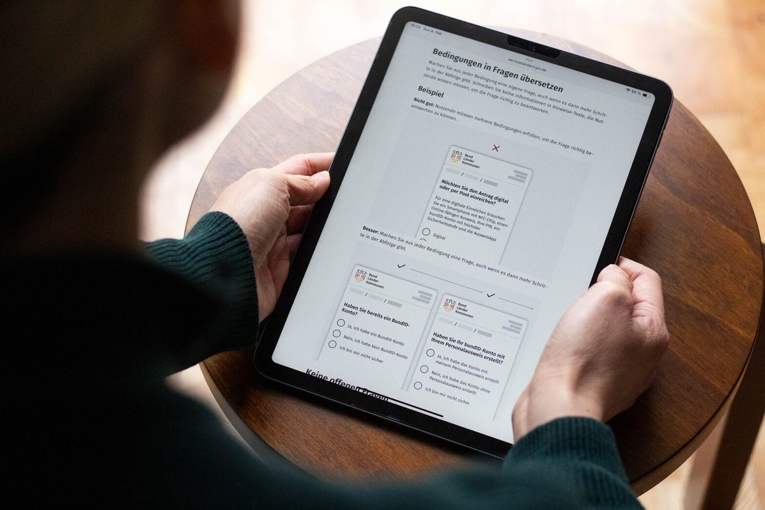 A person holding a tablet computer displaying a government design form guidance including dos and don’ts.