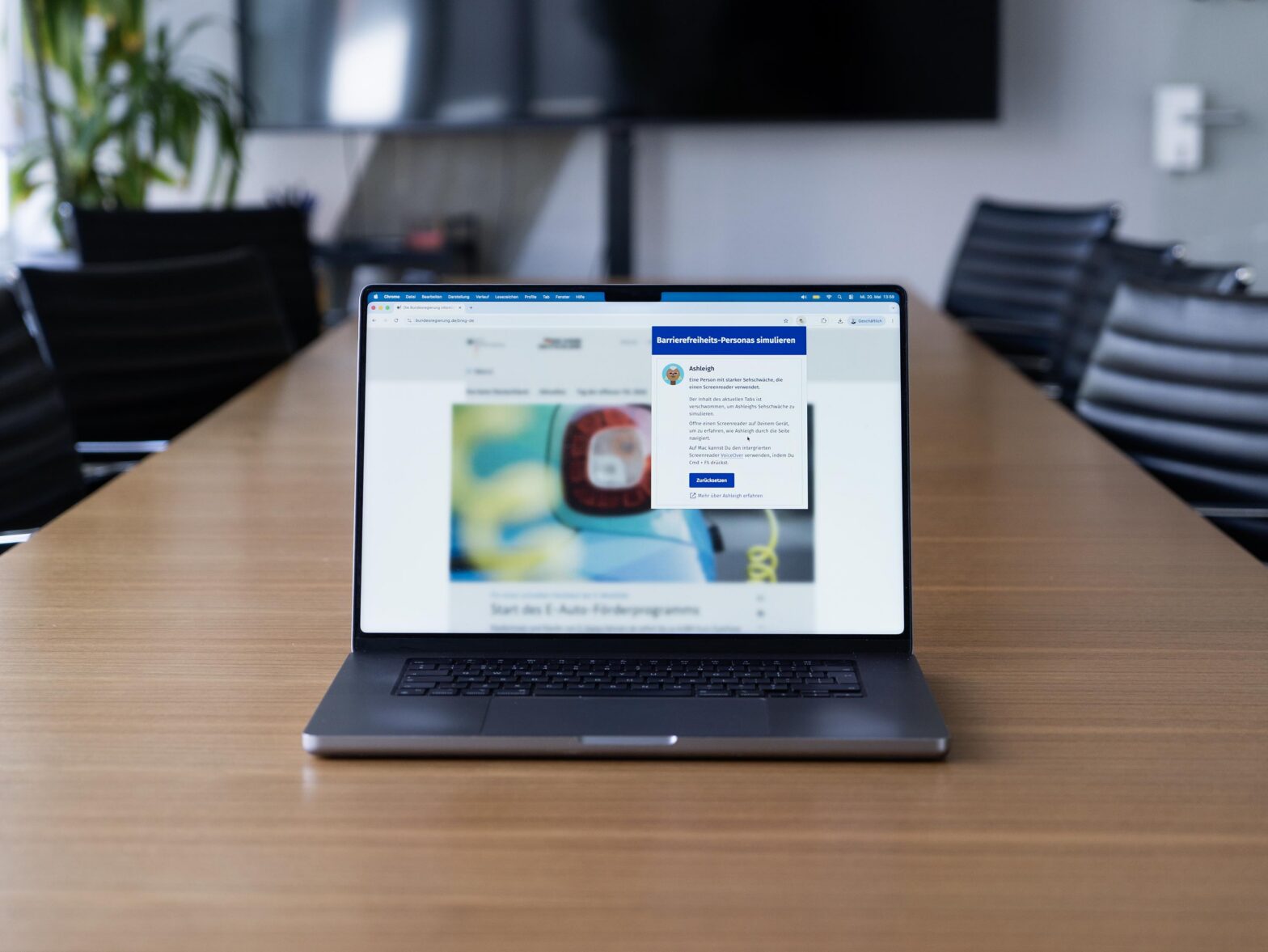 A laptop on a table, displaying a severely blurred website in a web browser, with a window overlaid on top – for a visually impaired accessibility persona named Ashleigh
